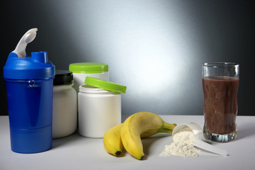 Sport Nutrition Supplement containers with glass of cocktail