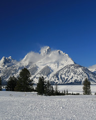 Snow mist blowing off Grand Teton peaks  in front of snowfield in Wyoming United States