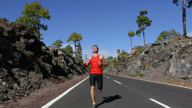 Sprinting runner man running at fast speed. Male sport sprinter training hard. Young strong male fitness model during run outdoors in beautiful landscape. Real time.