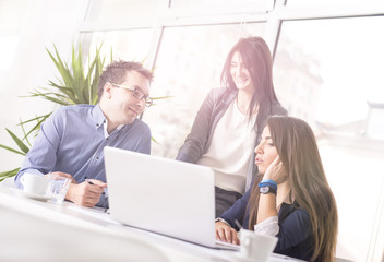 Successful business people interacting, discussing and sharing ideas in bright modern office. Teamwork concept. Focus on man. Lens flare effect