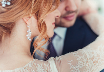 closeup of the unrecognizable bride and groom with a focus on the jewelry earrings and wedding hairstyle