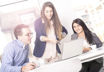 Obraz premium Successful business people interacting, discussing and sharing ideas in bright modern office. Teamwork concept. Focus on girl in the middle, Lens flare effect