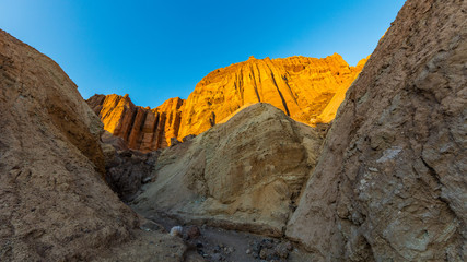 Red Cathedral seen from the Golden Canyon trail. Narrow canyon with vertical walls on both sides. Rocky landscape background. Sandstone formations in Golden canyon, Death Valley