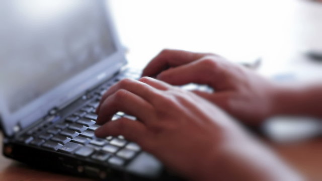 Businessman using laptop at kitchen table, working from home.