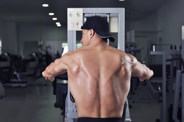 Fototapeta na wymiar Handsome powerful athletic man performing back exercise. Strong bodybuilder with perfect muscles.