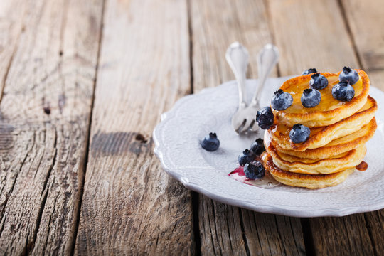 Pancake folded stack of with liquid honey and fresh blueberries on wooden background.Copy space.selective focus.