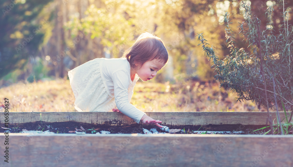 Wall mural Happy toddler girl playing in the garden