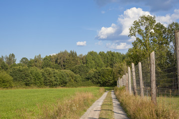 Fototapeta na wymiar View of a path with a fence in the green countryside in Sweden