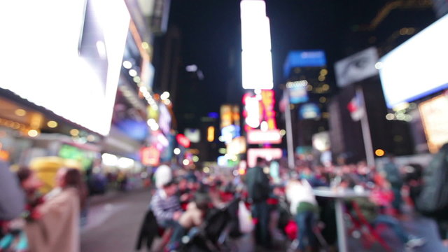 People at Times Square, New York City background at the red chair. Out of focus city lights, people walking and billboards at night defocused blurry. Manhattan city life backgrounds.