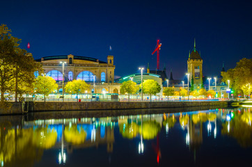 night view of the main train station in the swiss city zurich reflecting on surface of the limmat...