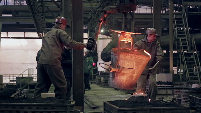 Worker on steel plant operates with molten metal. HD.