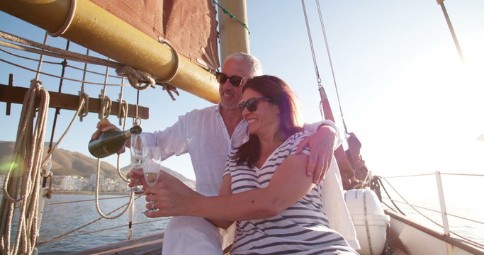 Mature couple celebrating with champagne on a sunset yacht cruise