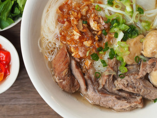 asian noodle soup with pork meatball with fresh vegetable on wood table vintage style, simply food, street food, hot and spicy noodle soup, asian food