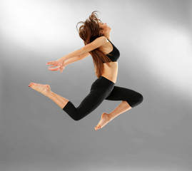 Fototapeta na wymiar Young sporty woman jumping on grey background