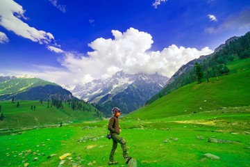 man standing in field with snow mountain and sunny day, Kashmir, India.