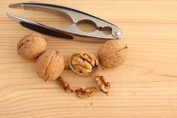 English or Persian walnuts and metal nutcracker on a wooden background.