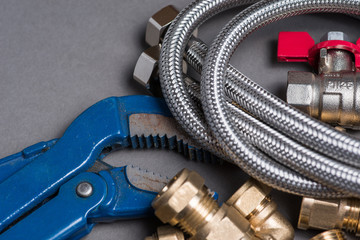 Adjustable spanner with assorted plumbing fittings and hose on grey