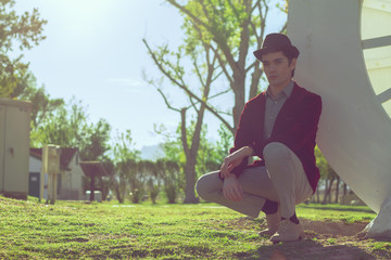 Portrait of young fashionable beautiful man in park wearing fedora