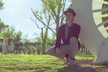 Fototapeta premium Portrait of young fashionable beautiful man in park wearing fedora