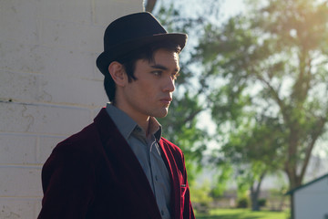 Portrait of young fashionable beautiful man in park wearing fedora
