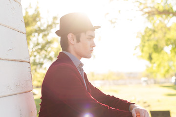 Portrait of young fashionable beautiful man in park wearing fedo
