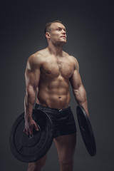 Fototapeta na wymiar Shirtless bodybuilder holds lifting weights.