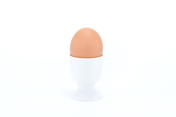 Boiled egg in egg cup on white background.
