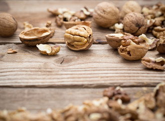 Walnut kernels and whole walnuts on rustic old wooden table