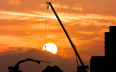 silhouette of excavator and crane working sunset background