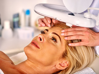 Naklejka premium Woman middle-aged in spa salon with young beautician. Tweezing eyebrow by beautician. Aesthetic medicine.