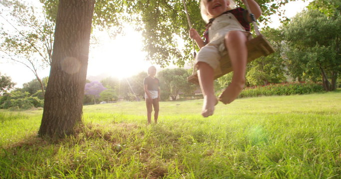 Playful boy pushing his little brother on swing at park