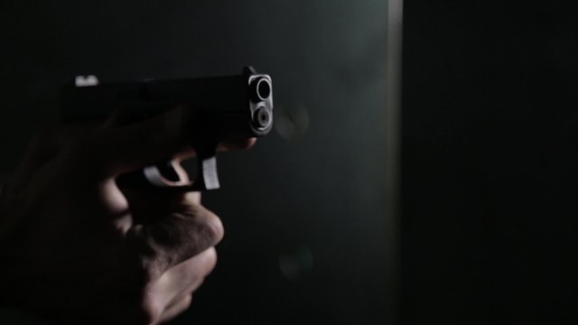 Aiming and shooting a pistol over black background