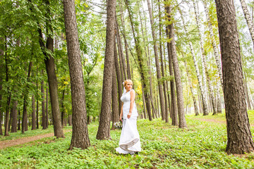 Young bride in wedding dress holding bouquet, outdoors