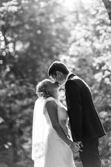 Beautiful wedding couple in park. They kiss and hug each other