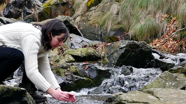 Beautiful woman washing face with clean water mountain river