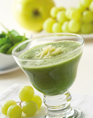 A glass of healthy juice made with spinach, apple and grapes