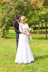 couple in wedding attire with a bouquet of flowers, bride and groom outdoors