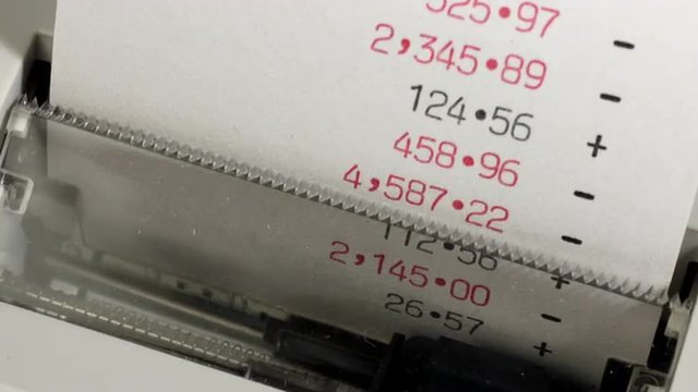 Zoom in to an calculator adding machine print out with positive figure in black and negative debt figures in red. Time lapse.