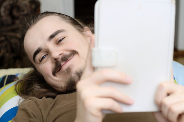 Smiling bearded man reading ebook