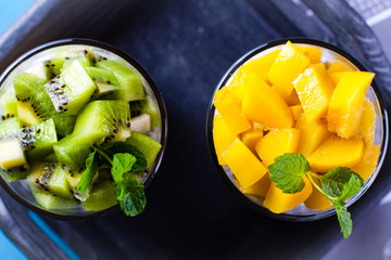 Dietetic dessert in the form of a fresh fruit salad with kiwi and peach with chia seeds and yoghurt served in a glass.Looking at the scene from above.