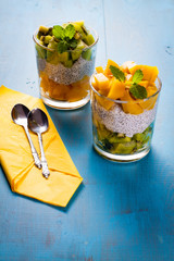 Dietetic dessert in the form of a fresh fruit salad with kiwi and peach with chia seeds and yoghurt served in a glass.