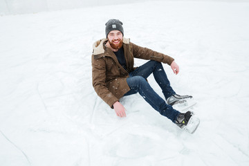 Fototapeta na wymiar Man sitting on the snow in ice skates