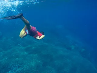 Fototapete Tauchen Man in red swimsuit dives to the coral reef  © Elya.Q