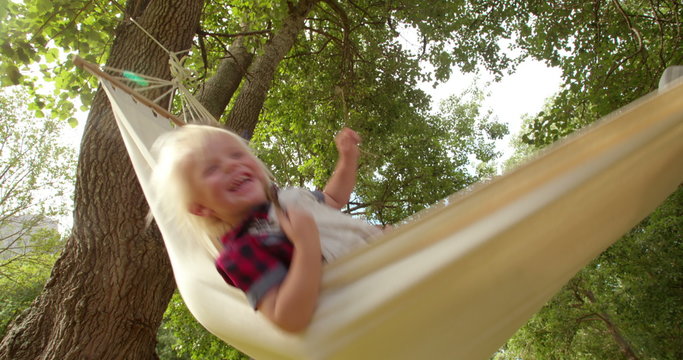Lovely dad hugs his blond child on a hammock