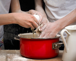 The process of kneading dough. Human Hands break an egg into the dough 