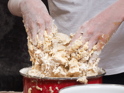 The process of kneading dough. human hands Close. The dough is made of flour. Kitchen pasuda - red pot 