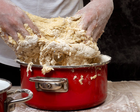 The process of kneading dough. human hands Close. The dough is made of flour. Kitchen pasuda - red pot 