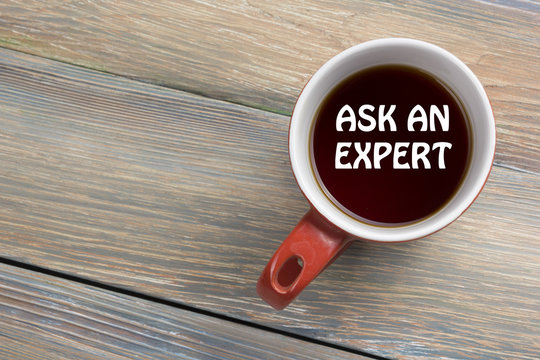 Ask an expert. Coffee cup with message. Office desk table top view.