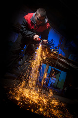 Young man working with plasma cutter on steel plate