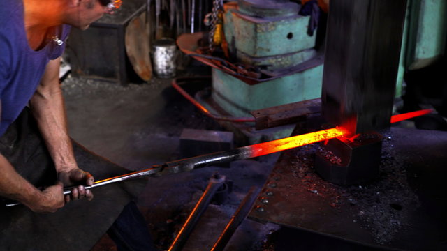Mechanical hammering of glowing iron in blacksmith forge
